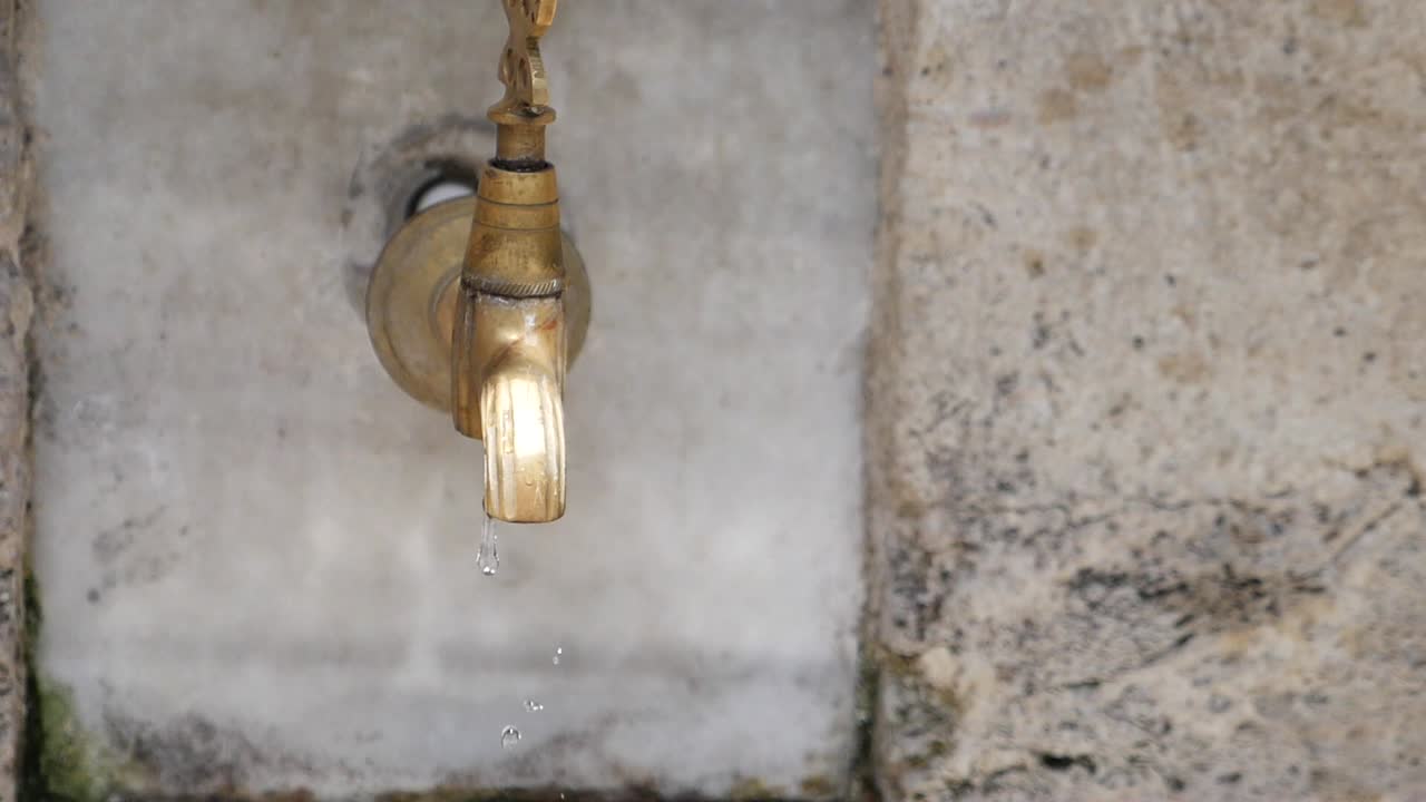 cerca de un viejo grifo de bronce goteando agua