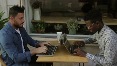 Hombres-Multiétnicos-Que-Usan-Computadoras-Portátiles-En-La-Cafetería.