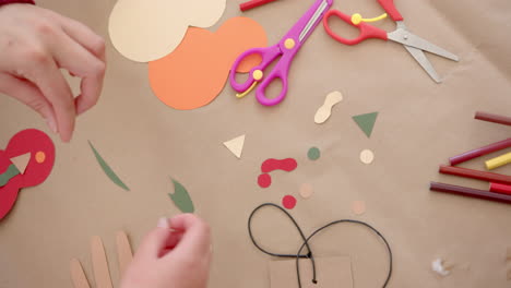 happy biracial mother and daughter sticking colourful cutouts in sunny living room