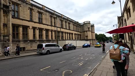 police car driving past historic college building