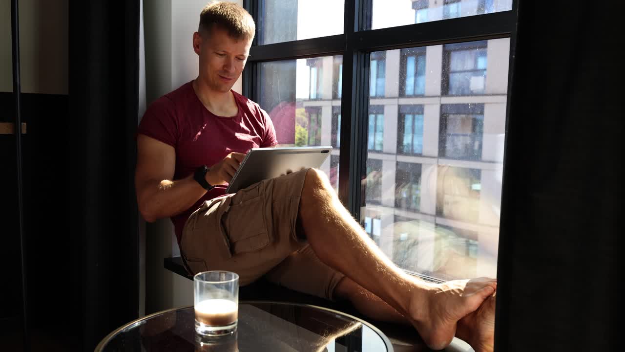 Man using a tablet while sitting by the window