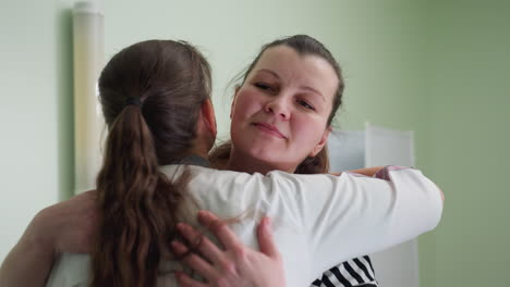 woman approaches nurse inside clinic room and receives warm comforting hug with relief visible on her face conveying emotional support and trust in medical care during personal health consultation