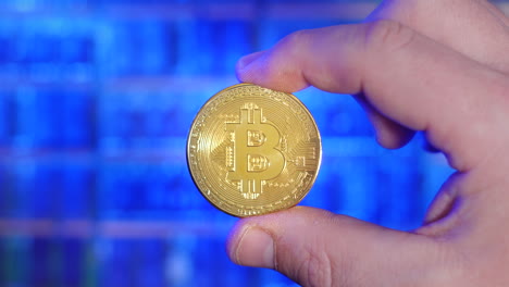 rack focus portrait of bitcoin gold coin being held between fingers