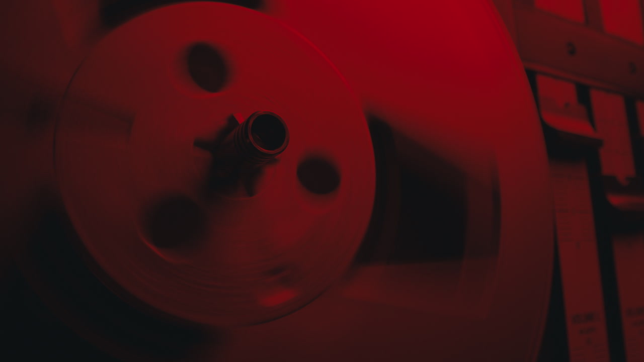 A close-up on a vintage tape recorder in a red blinking light