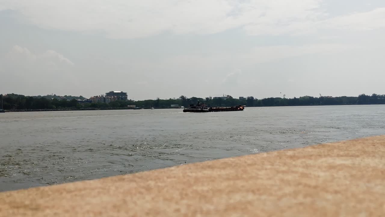 Mandovi River with Cargo Ship Sailing, trees and buildings at reis magos, panaji, goa, india. day time, stable shot, 4k