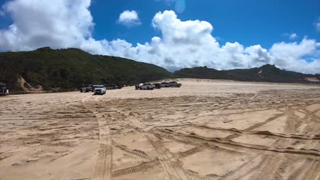 punto de vista de conducción mirando hacia atrás de una concurrida playa de queensland en un lugar turístico popular con varios camiones 4x4 en eli creek de la isla de fraser - ideal para el reemplazo de la pantalla verde de la escena interior del automóvil