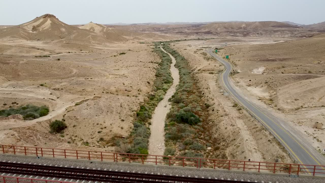 사막과 그 옆에 있는 빈 도로가 보이는 다리 아래 마른 개울의 공중 전방 느린 드론 샷