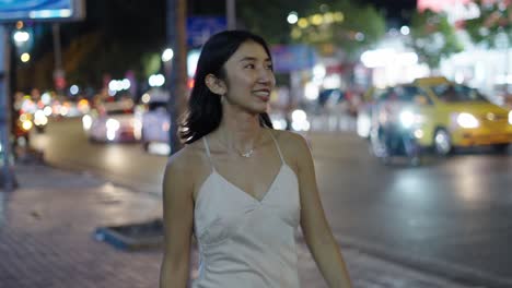 young woman using smartphone on city street at night