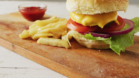 video of cheeseburger, chips and bowl of ketchup on wooden board