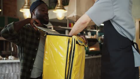 un trabajador del mercado ayuda a un repartidor de alimentos a hacer un pedido, después de lo cual dan cinco en aprobación. trabajo en equipo persona negra y persona europea