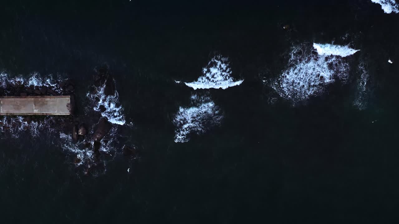 Aerial View of a Jetty with Waves Crashing on Rocks