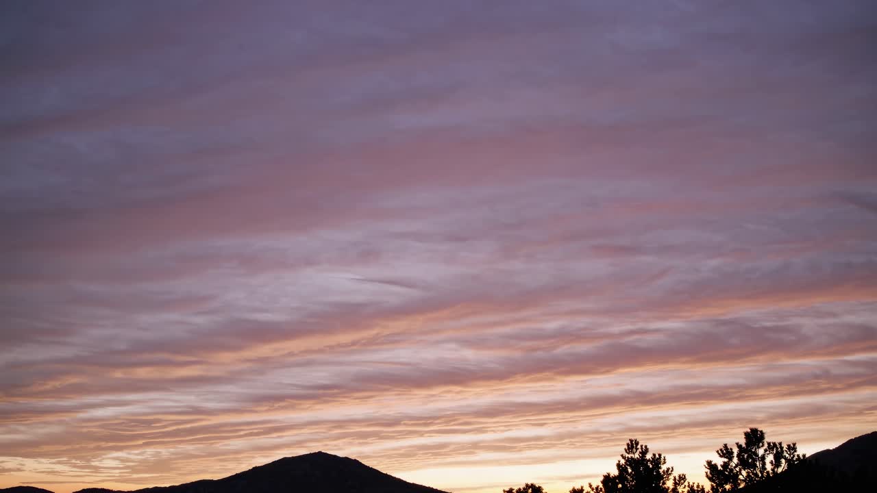 A serene sunset video captures a wide-angle view of silhouetted mountains and trees
