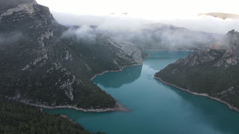 Aerial-views-in-a-famous-Canyon-in-Spain-with-clouds-in-between-and-a-reservoir-below