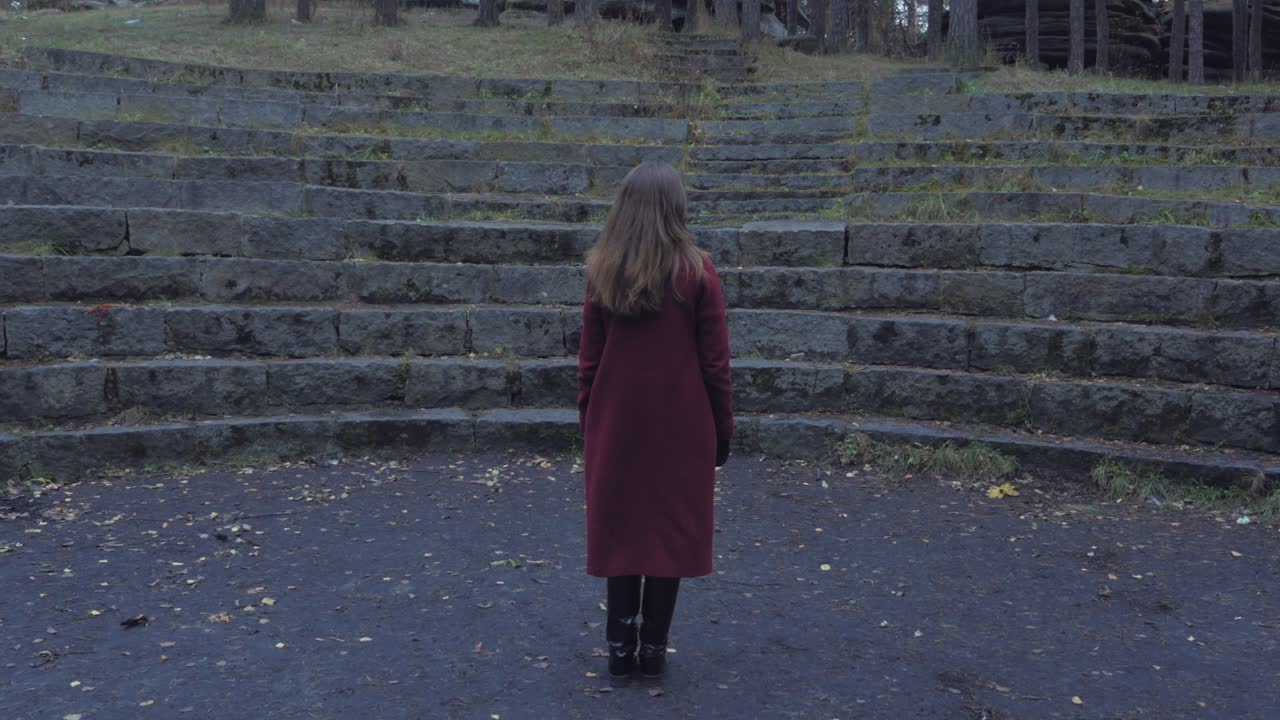 공원 에 있는 돌 암피테이터 에서 빨간 코트 를 입은 여자
