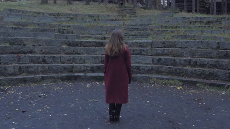 woman in red coat at stone amphitheater in park