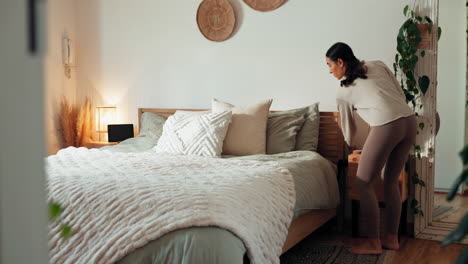 woman making bed in cozy bedroom