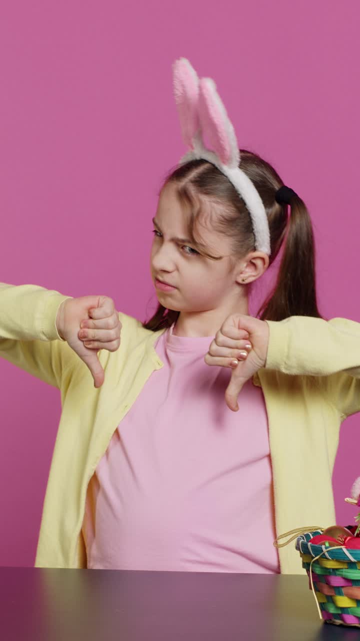 Little Girl Wearing Bunny Ears Shows Disapproval with Thumbs Down
