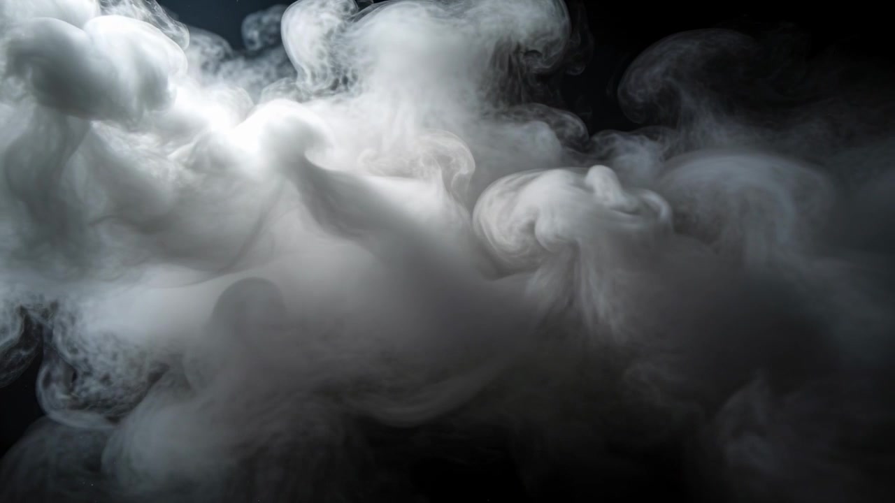 Densa colonna di fumo bianco-grigio che si espande, si sposta a destra e si arriccia in uno studio buio, illuminata da un riflettore.