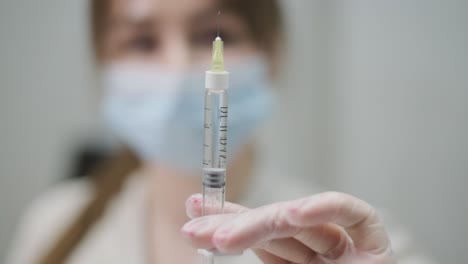 imagen de enfoque selectivo de la mano de un profesional de la salud sosteniendo una jeringa, con un fondo borroso que hace hincapié en el instrumento médico
