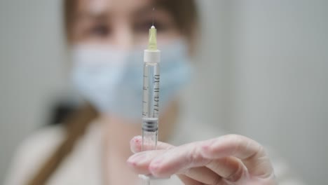 selective focus image of a healthcare professional's hand holding a syringe, with a blurred background emphasizing the medical instrument