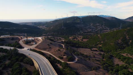 Vuelo-De-Drones-Al-Atardecer-Con-Autos-Pasando-Por-La-Carretera-De-Abajo-En-Tarifa,-España