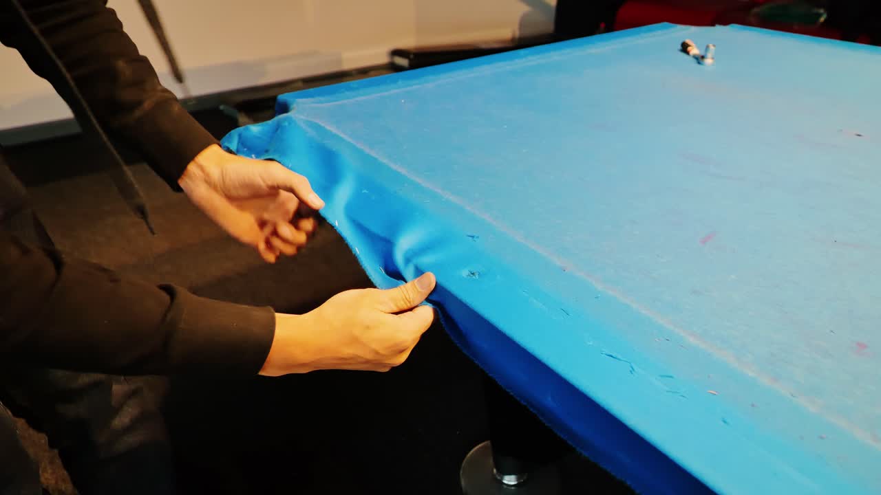 Restoration of worn billiard table as blue felt is carefully removed by hand, 4k