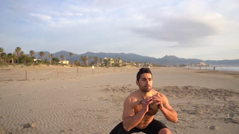 man doing functional exercises with kettlebell on the beach at sunrise in slow motion
