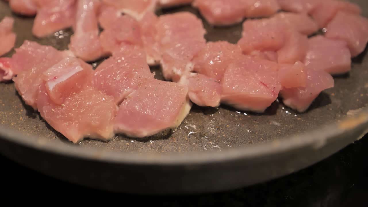 Handheld close-up of turkey meat cooking on pan, capturing details and texture.