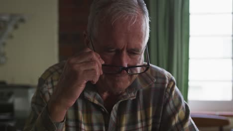 senior man taking off his glasses at home