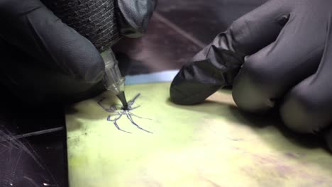 a tattoo artist with black gloves drawing the tattoo of a spider