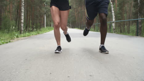 Man-And-Fit-Young-Woman-Chatting-And-Running-Along-Forest-Road-In-Morning