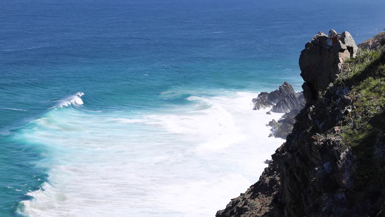 파도가 은 파란 하늘로 바위가 있는 해안에 부히고