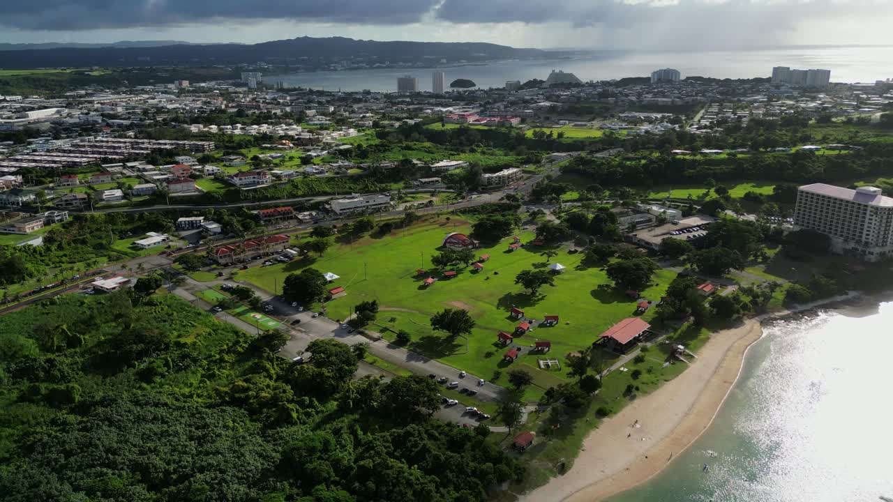 Stunning aerial flyover of coastal public Ypao Beach park with lush greenery at Guam, USA during daytime