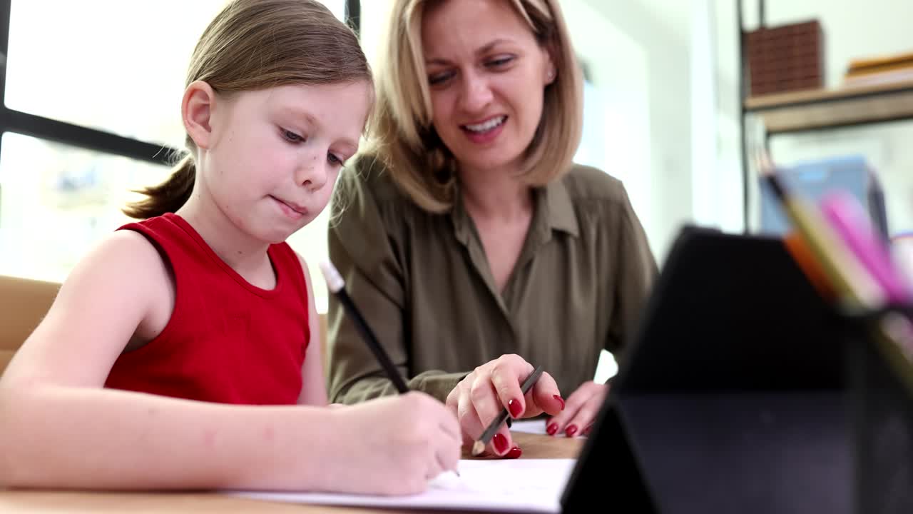 Giovane madre premurosa che studia con la figlioletta scolaretta