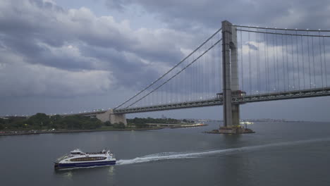 aerial view of a ferry passing the verrazano-narrows bridge on an overcast summer day. shot in new york city