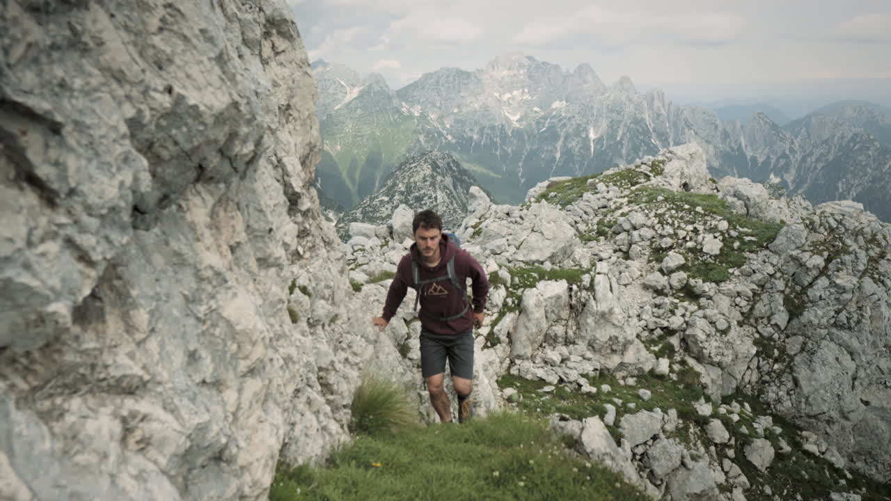 caminante de seguimiento de cámara en frente en un camino de hierba verde hacia la cima de la montaña