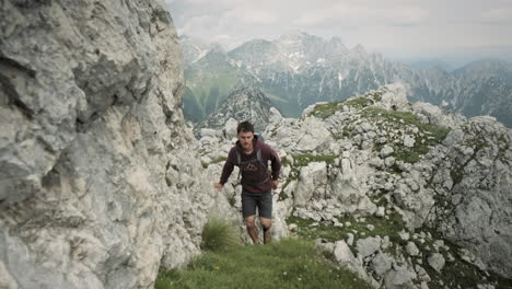 camera tracking hiker in front on a grenn grassy path towards the top of mountain