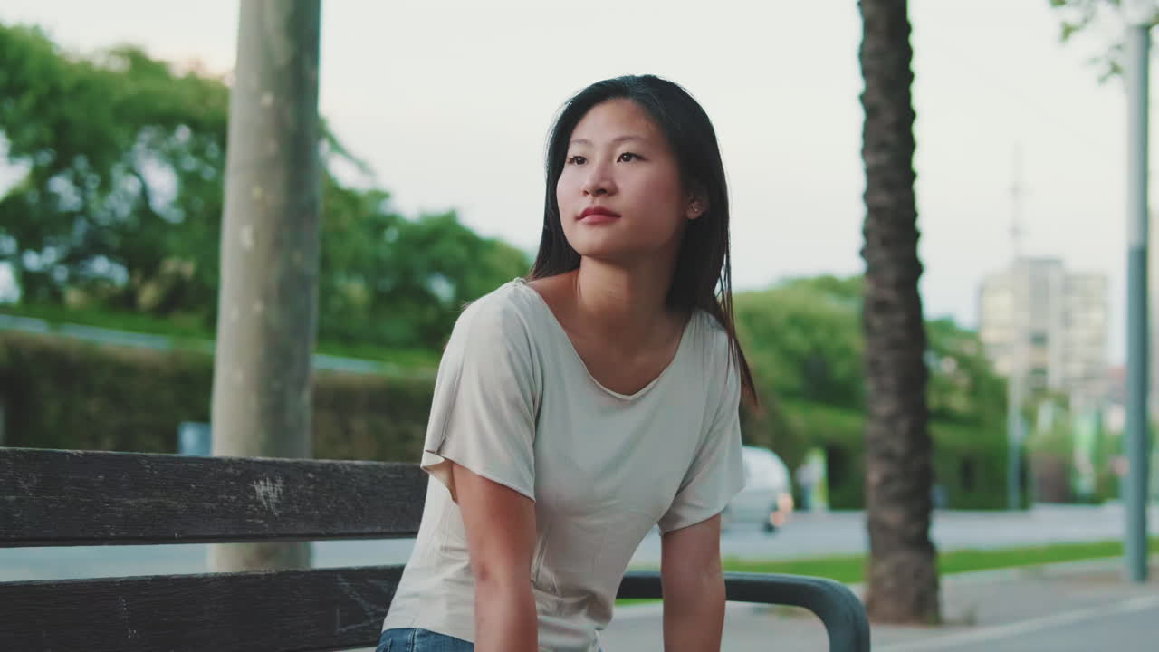 도시의 벤치에 앉아 있는 젊은 여성