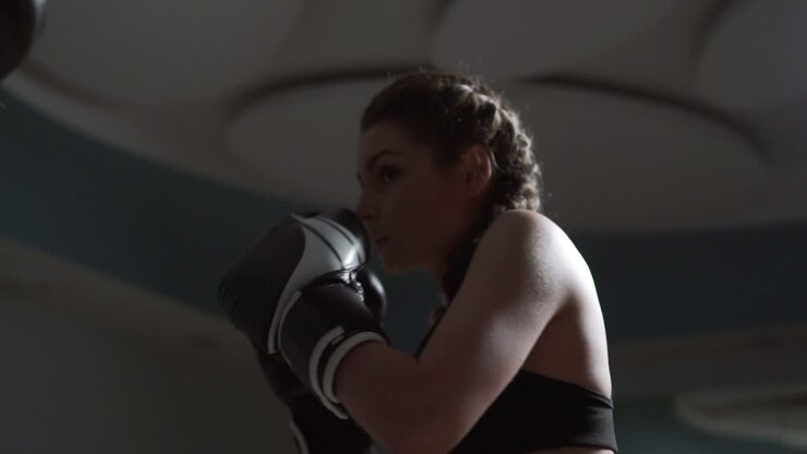 Young attractive woman in boxing gloves training with her couch in a boxing club. Slow motion shot