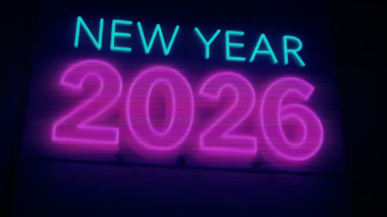 Inizio del movimento della telecamera, operatore che esegue una panoramica dell'insegna al neon CAPODANNO 2026 di notte, rivelando le vetrine dei negozi