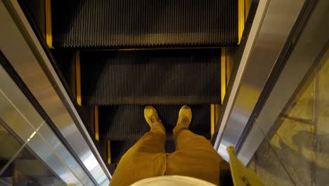 vista desde arriba en los pies de zapatillas de deporte del hombre usando escaleras mecánicas móviles