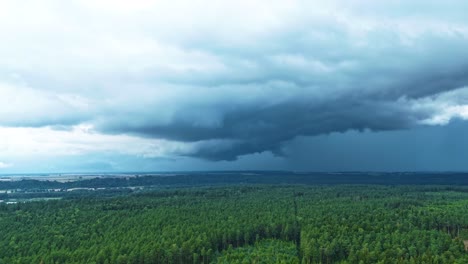 powerful nature - storm clouds flowing in above woodland, aerial time lapse view