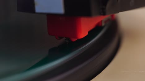 colocando la aguja del gramófono de cristal en el disco de vinilo verde giratorio, macro de cerca