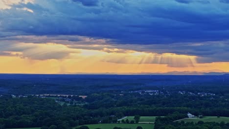 a drone fly-over of greenville county in south carolina showing a landscape of trees, mountains, and storm clouds.