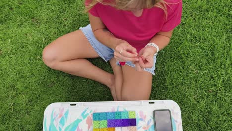 woman beading in the grass