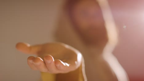 Backlit-Shot-Of-Man-With-Long-Hair-And-Beard-Representing-Figure-Of-Jesus-Christ-Extending-Hand-In-Friendship-Towards-Camera