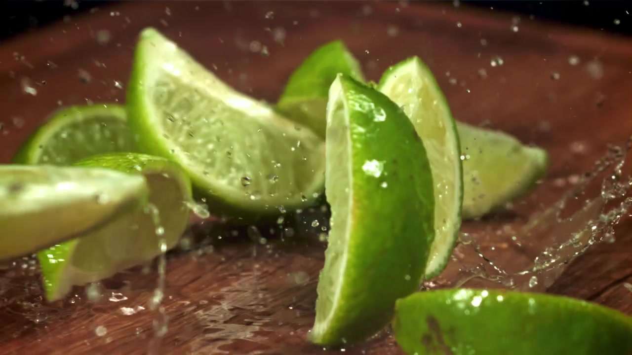 Slow Motion of Fresh Lime Wedges Dropping onto a Wet Wooden Board