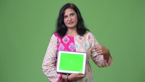 mature beautiful indian woman showing digital tablet and pointing finger