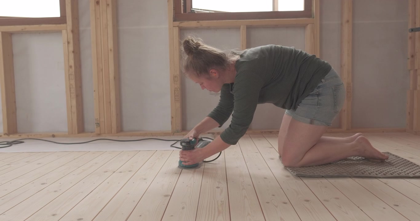Woman sanding down a wooden floor