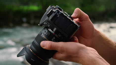 hombre con las manos sujetando una cámara fotográfica al aire libre. fotógrafo masculino usando una cámara digital